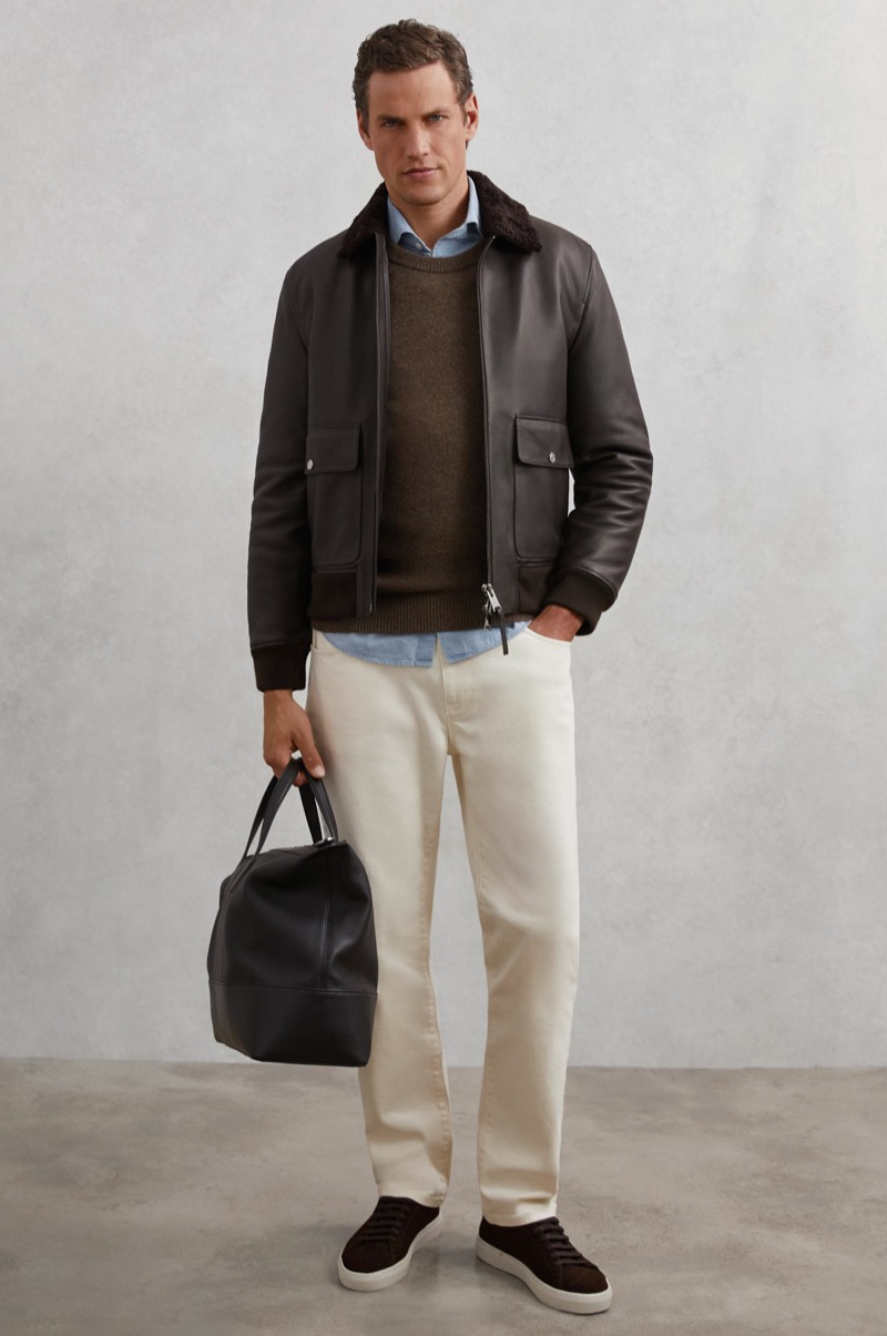 pale blue denim shirt under dark brown leather bomber and olive sweater with ecru jeans