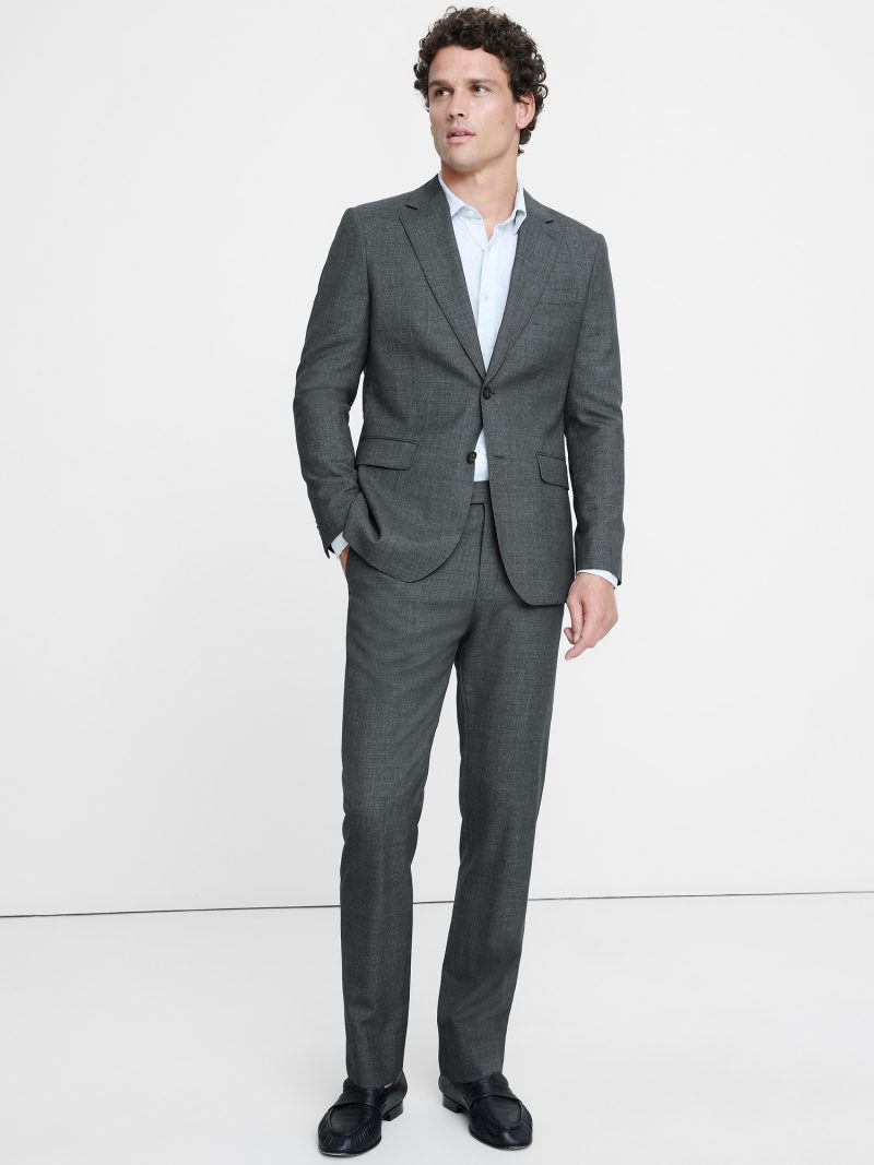 Model wears a gray suit with a light blue dress shirt and black leather loafers