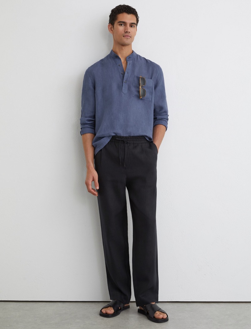 Model wears blue linen grandad collar popover shirt with drawstring pants and leather sandals