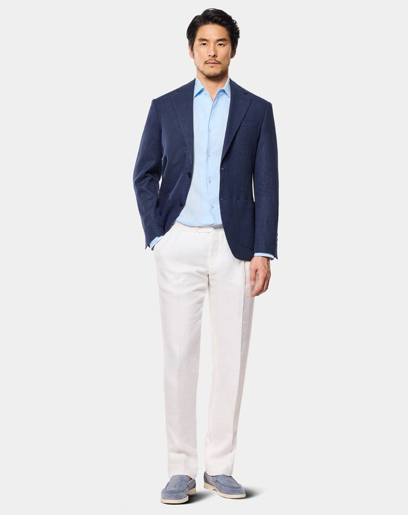 Model wears navy linen blazer with light blue linen shirt and ivory pleated trousers