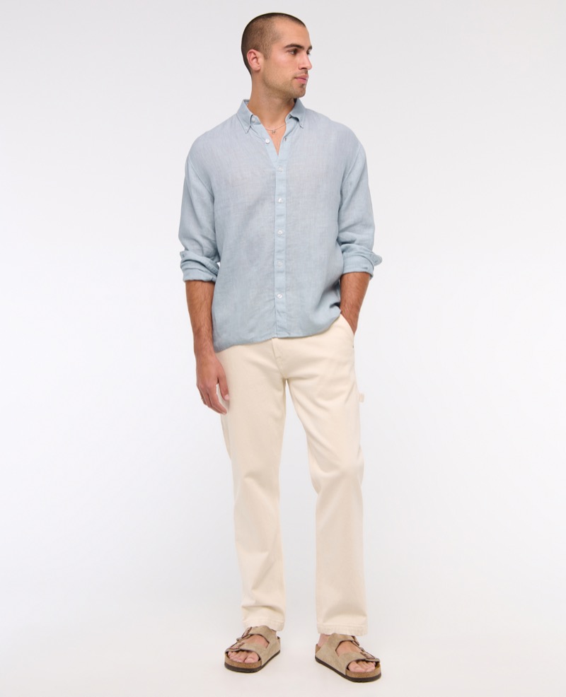 Model wears light blue linen shirt with ecru jeans and tan suede sandals