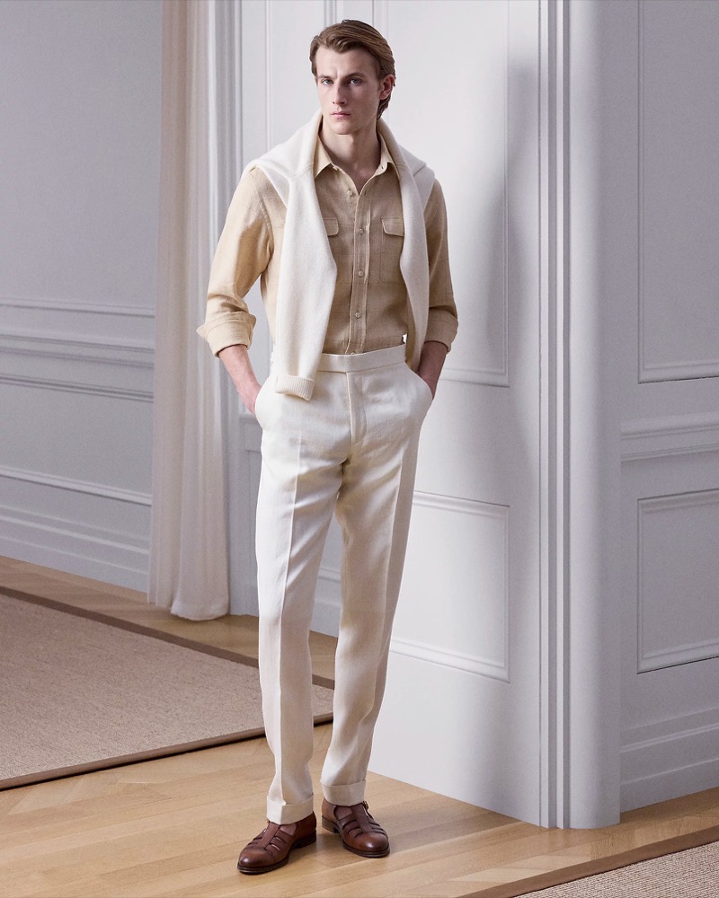 Model wears pale yellow linen two-pocket shirt with off-white pleated trousers and brown leather sandals