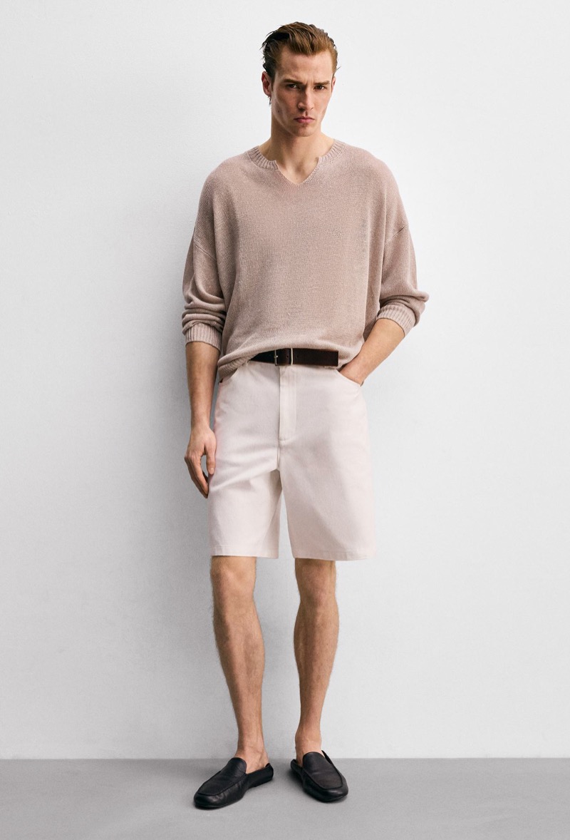 man wearing Bermuda shorts at knee length with a V-neck sweater and leather loafers
