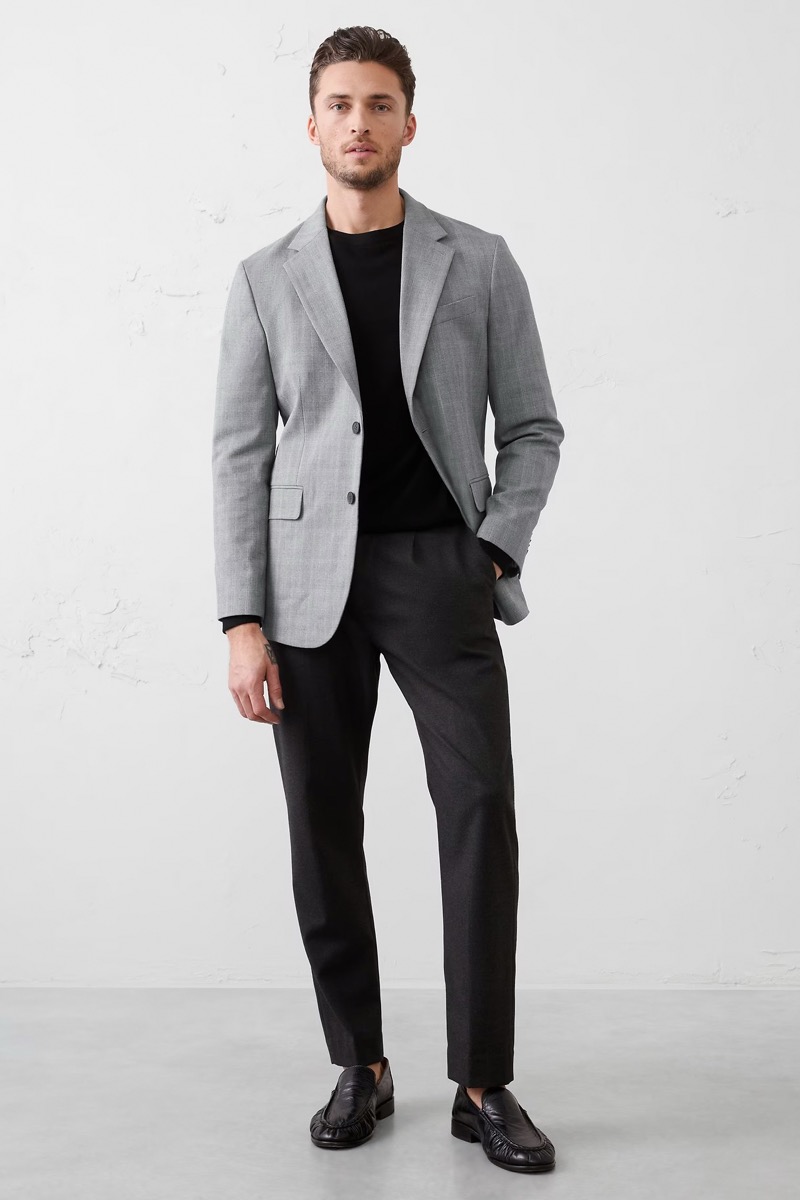 Man wearing black dress pants with gray check blazer over black crewneck sweater and black leather loafers