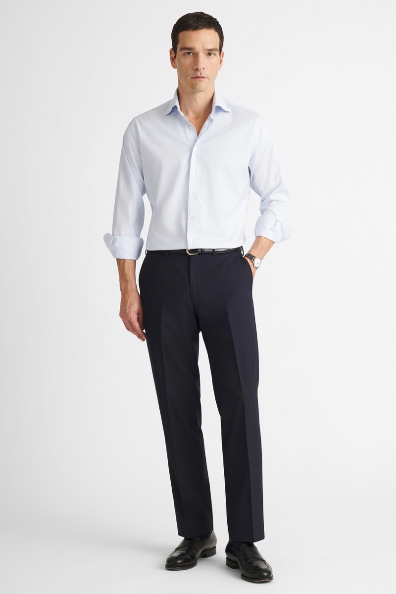 Man wearing black dress trousers with light gray dress shirt with rolled sleeves, black belt with gold buckle, watch, and black penny loafers