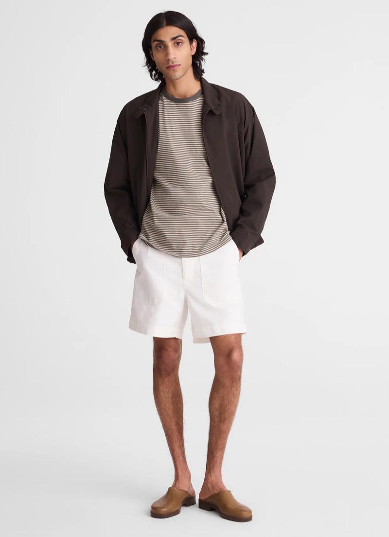 man wearing fatigue shorts in a military-inspired cut with a striped T-shirt, Harrington jacket, and leather mules