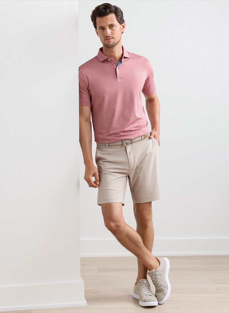 man wearing khaki golf shorts with a pink striped polo shirt and sneakers