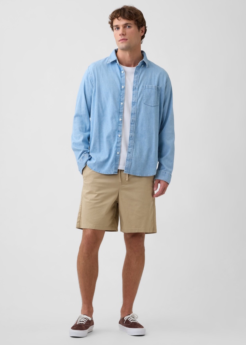 Man wearing khaki shorts with a light blue denim shirt and brown sneakers