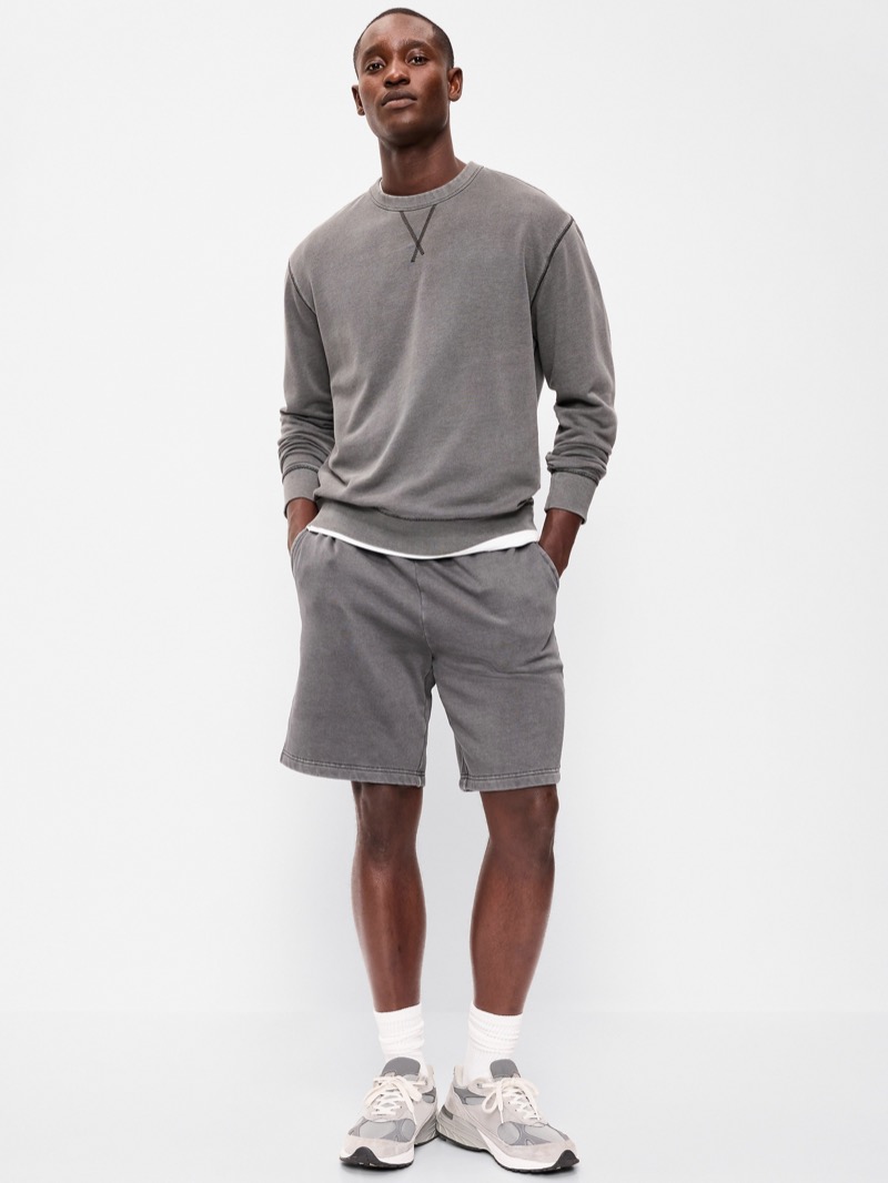 man wearing gray lounge shorts with a matching sweatshirt and sneakers