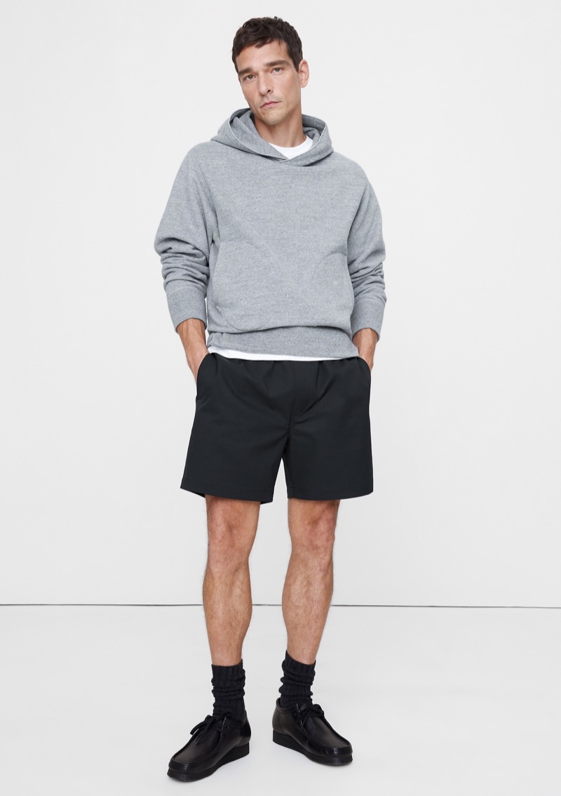 man wearing black performance pull-on shorts with a gray hoodie and leather chukka boots