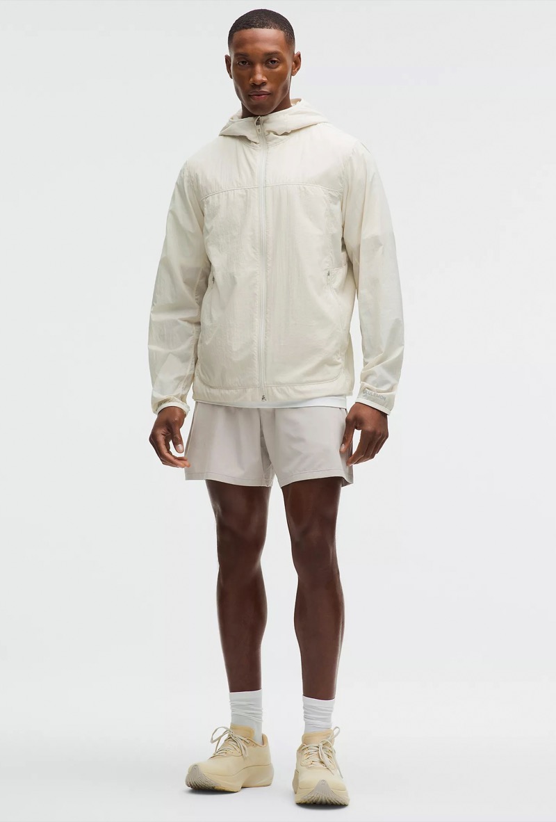 man wearing short beige running shorts with a windbreaker and sneakers
