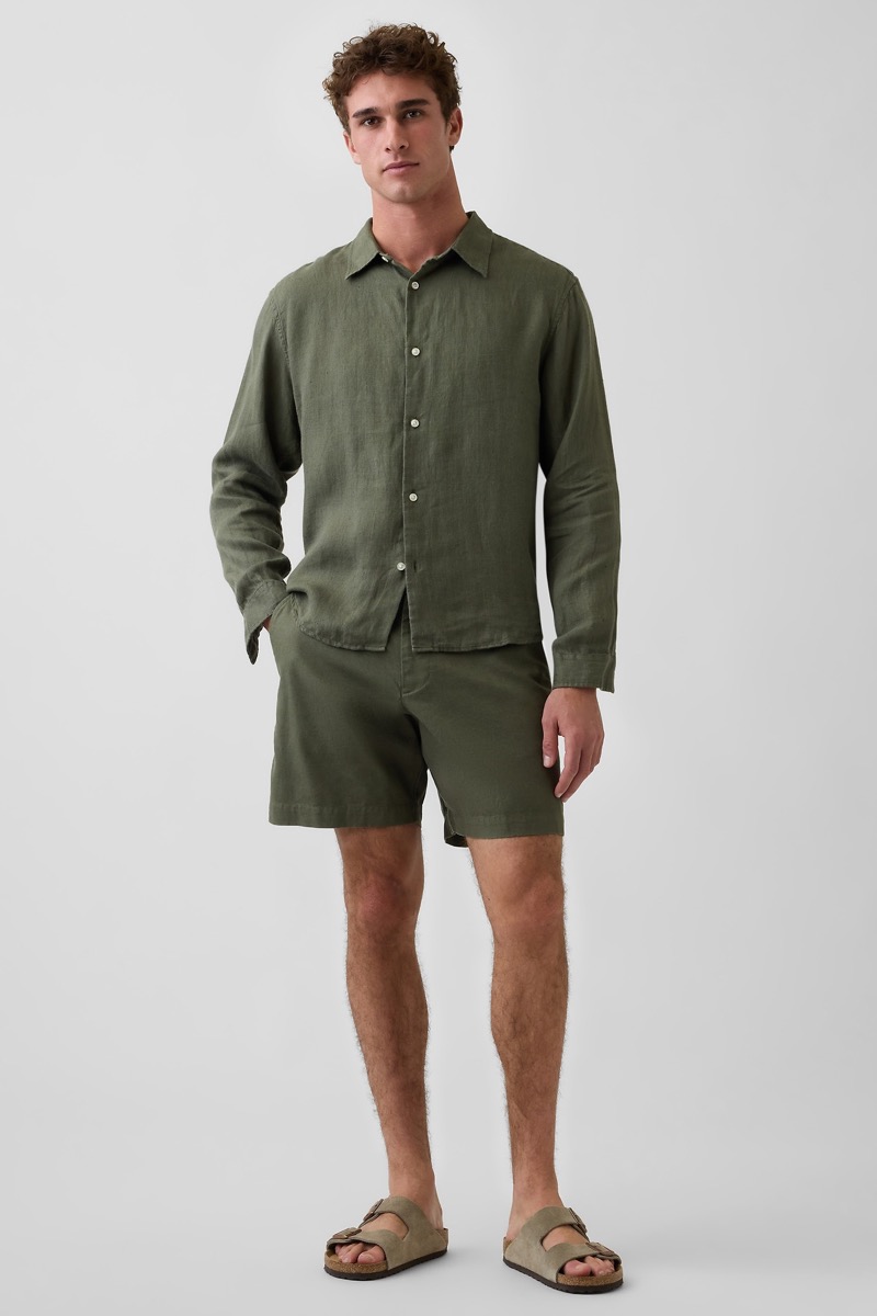 Man wearing an olive green linen long-sleeve button-down shirt with matching olive linen shorts and sand suede two-strap Birkenstock sandals