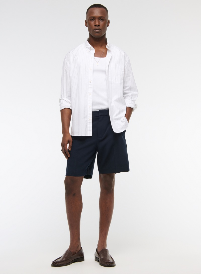 man wearing tailored dress shorts with a clean taper, a white button-down shirt, and brown leather loafers