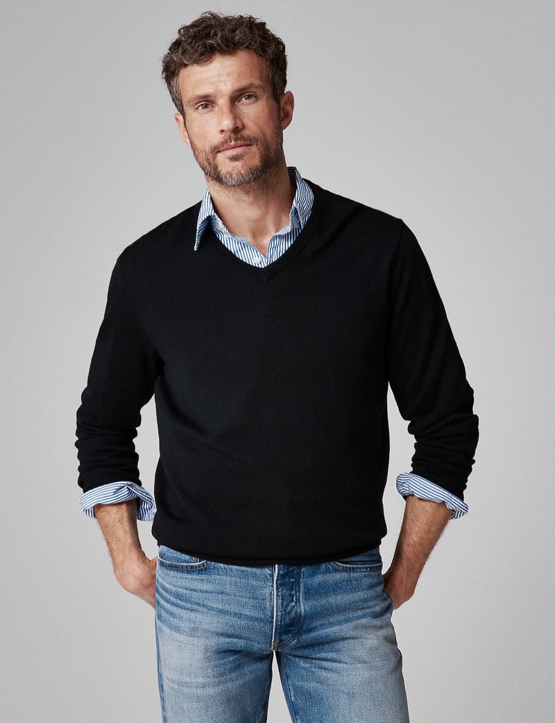 Black V-neck sweater layered over a striped dress shirt