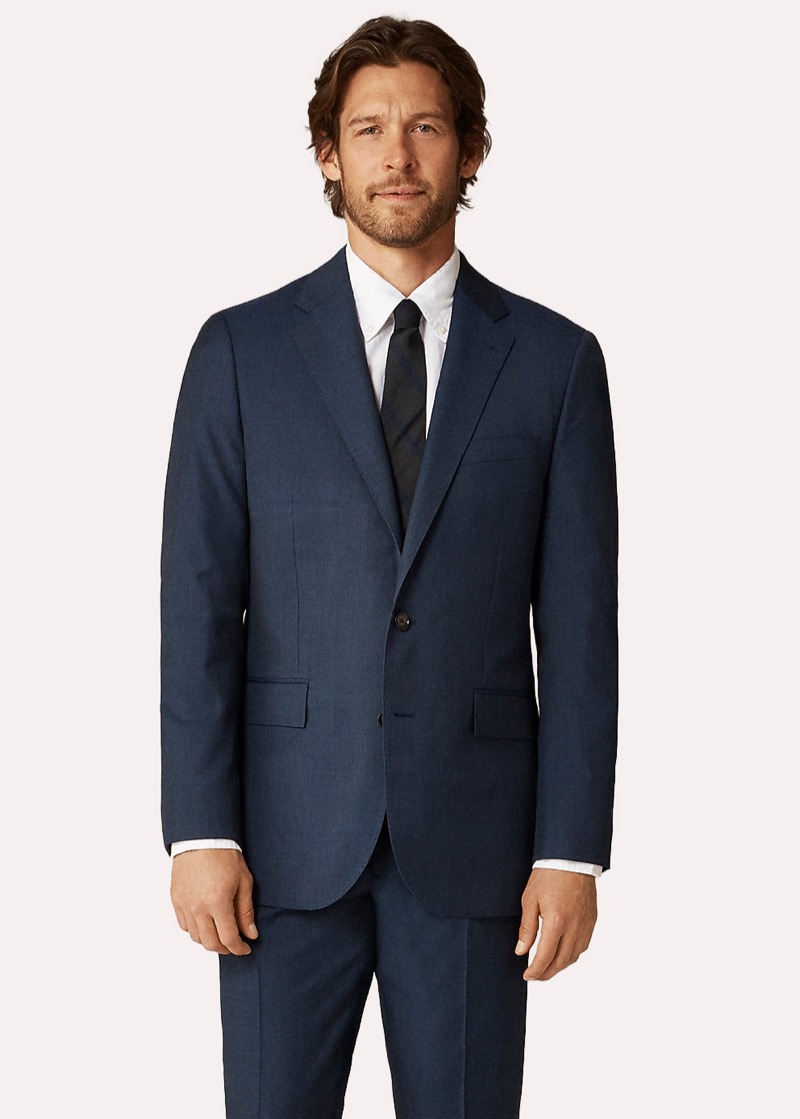 A man in a midnight-navy worsted wool two-button suit with notch lapels, paired with a crisp white spread-collar dress shirt and a charcoal silk tie.