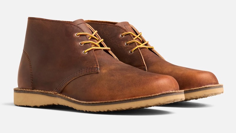 A pair of copper-brown waxed-leather chukka boots with three-eyelet lacing, yellow taslan laces, clean stitched seams, and a natural crepe rubber sole.