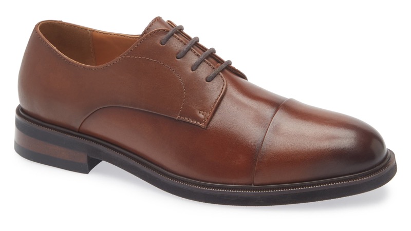 A single medium-brown polished leather cap-toe Derby shoe with open four-eyelet lacing, a stitched cap toe, brown laces, and a slim leather sole with a low stacked heel.