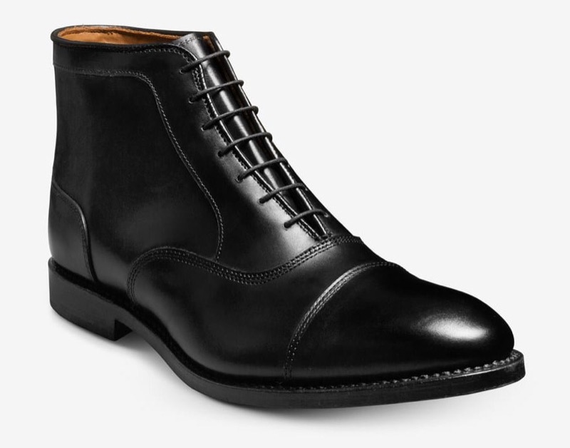 A black leather ankle-height cap-toe dress boot with five-eyelet lacing, a clean stitched cap, and a slim leather sole with low stacked heel.
