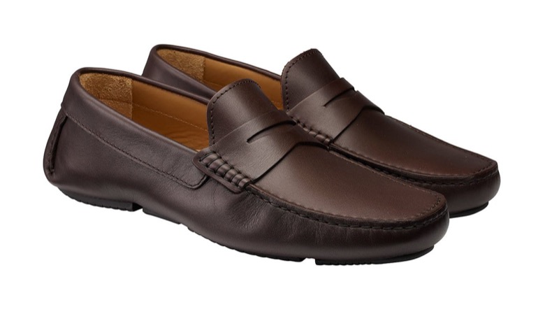 A pair of dark brown smooth-leather driving shoes with a penny-style apron strap, soft unlined construction, and a pebbled rubber sole that wraps up over the heel.