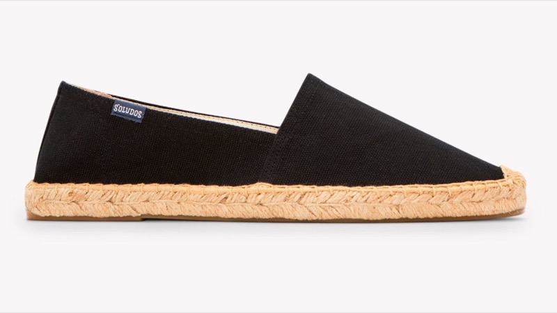 A black canvas slip-on espadrille in side profile with a tan jute-wrapped rope midsole and a thin rubber outsole.