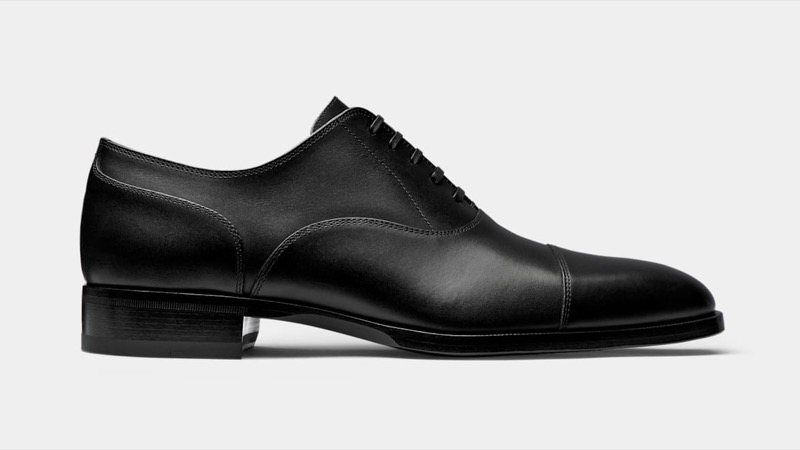 Side profile of a black leather cap-toe Oxford with closed lacing, a clean stitched cap toe, and a slim leather sole with low stacked heel.