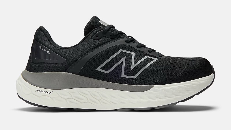 A black engineered-mesh running sneaker with a large reflective silver N logo on the side panel, a gray midfoot saddle, and a thick white Fresh Foam midsole.