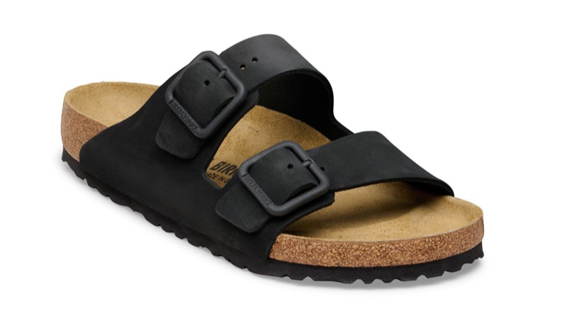 A single black oiled-leather two-strap sandal with antiqued metal buckles, a contoured natural cork-and-suede footbed, and a black EVA sole.