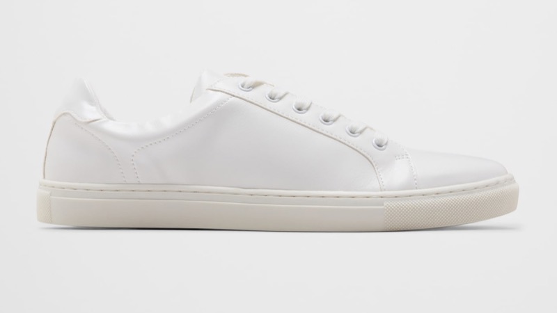 A side profile of a minimalist white leather low-top sneaker with a clean smooth-leather upper, seven-eyelet lacing, a stitched toe cap, a tonal heel tab, and a slim off-white rubber cupsole.