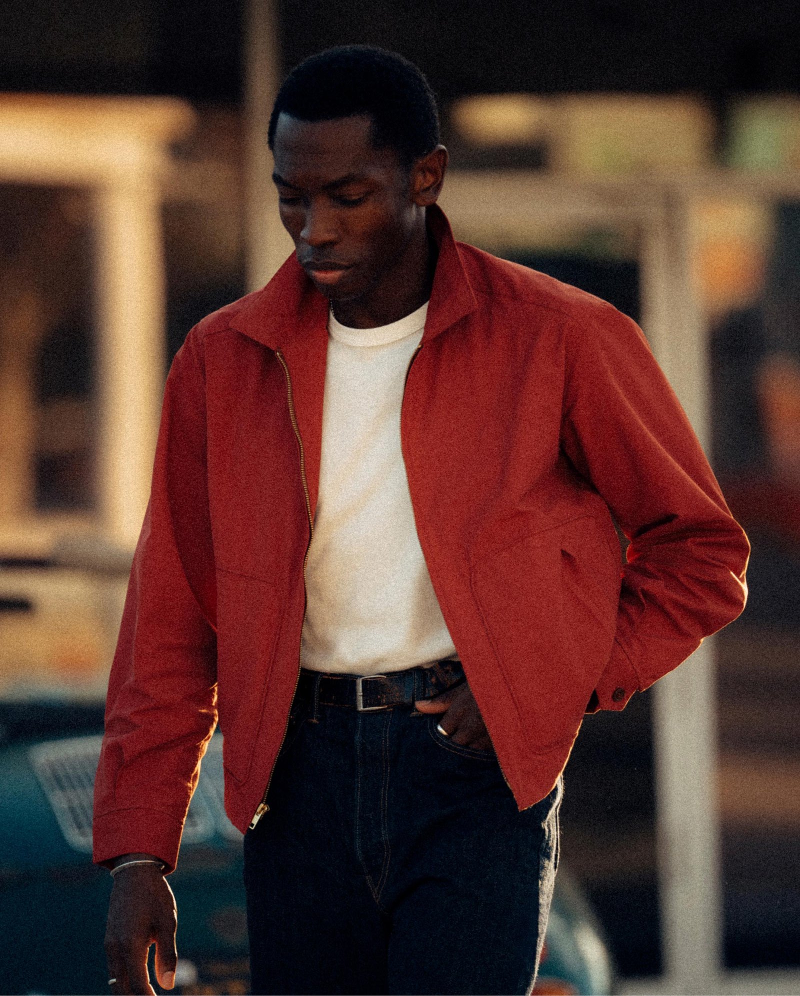 A short jacket hem leaves a clean line through the dark jeans.