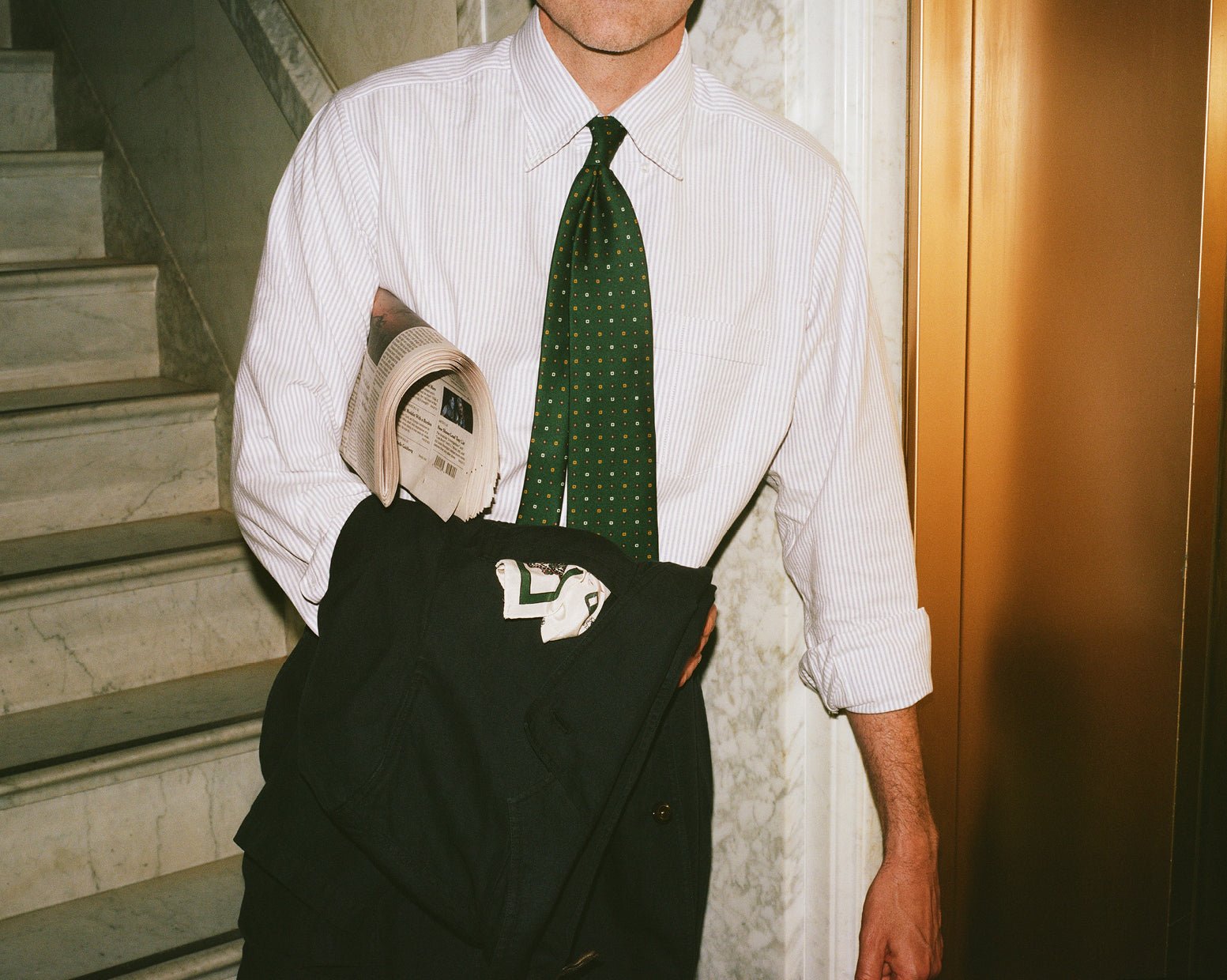 A green patterned tie brings color to a finely striped shirt.