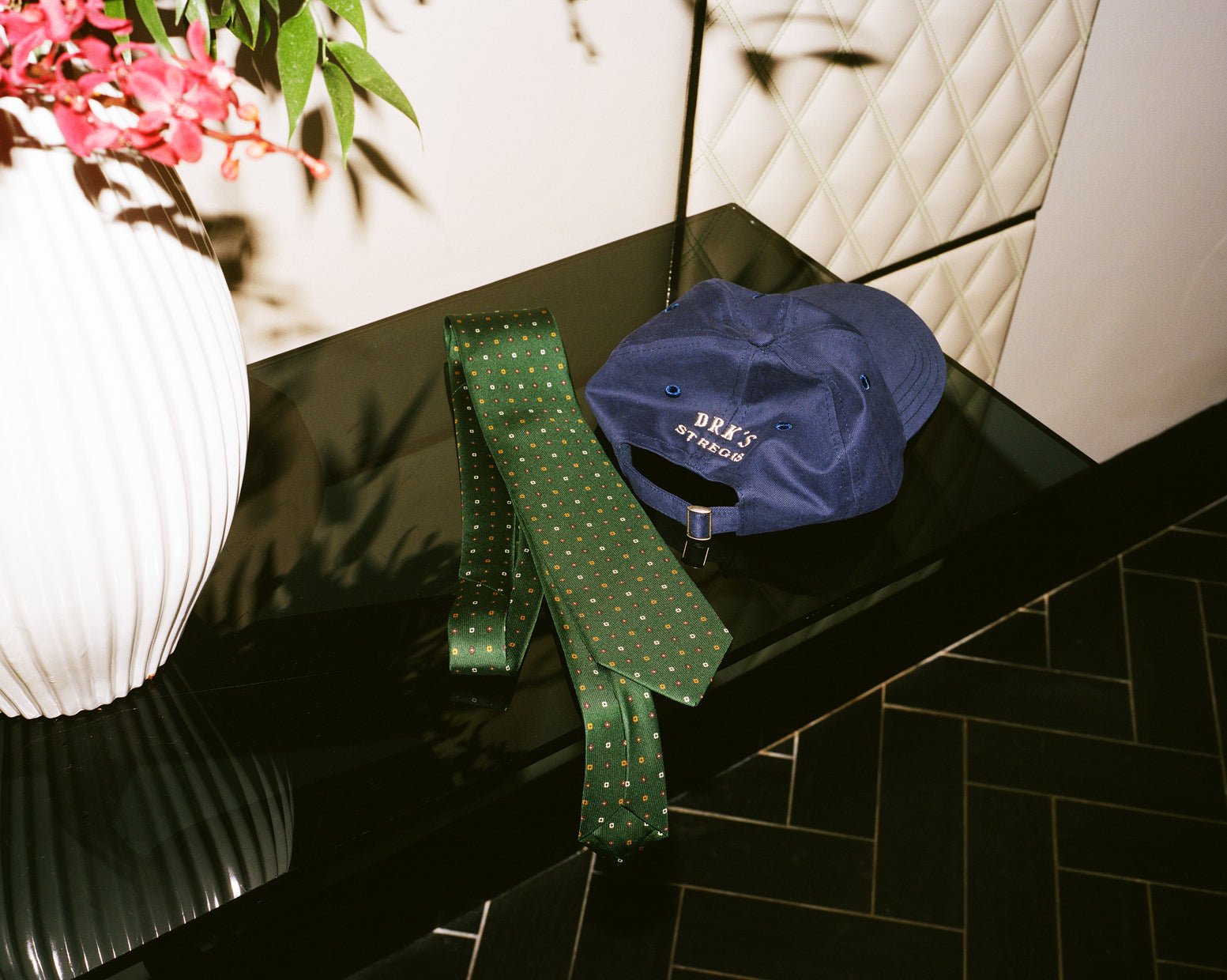 The green silk tie and navy cap from Drake’s collaboration with St. Regis.
