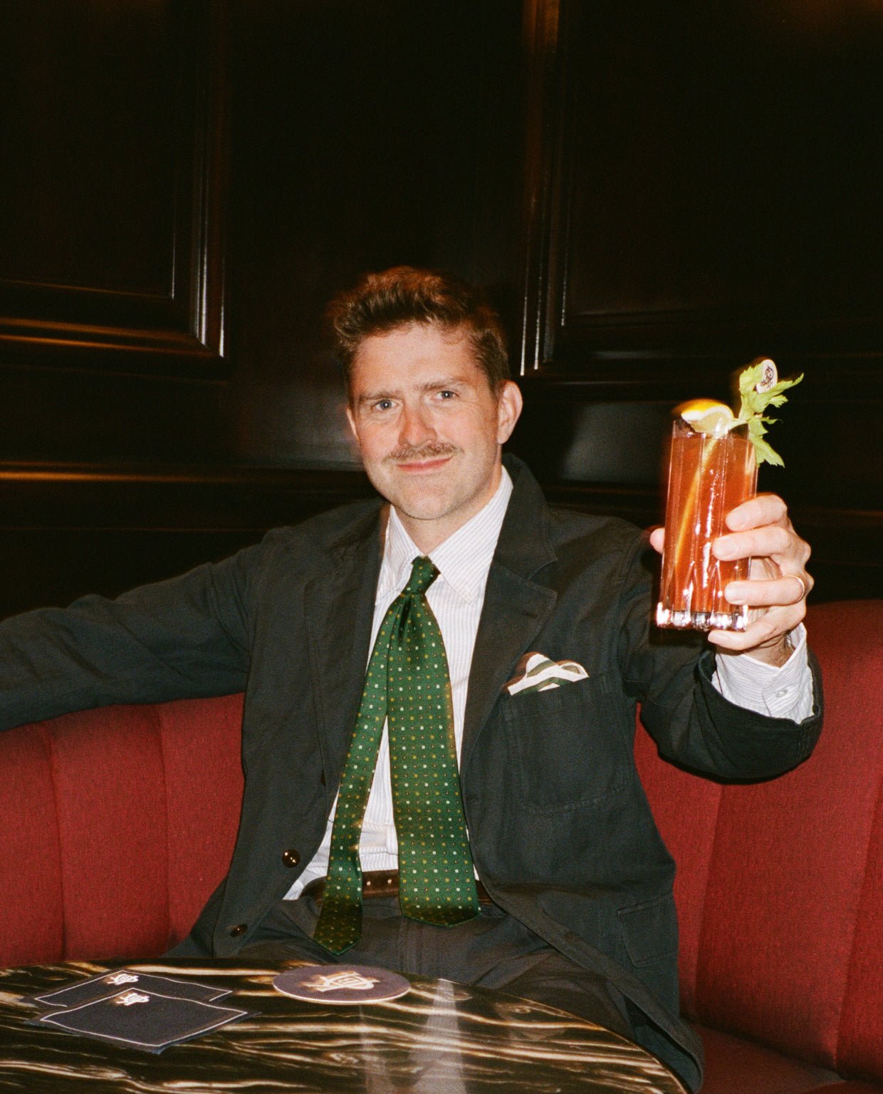 Bannister wears navy tailoring and the green tie over a striped shirt.