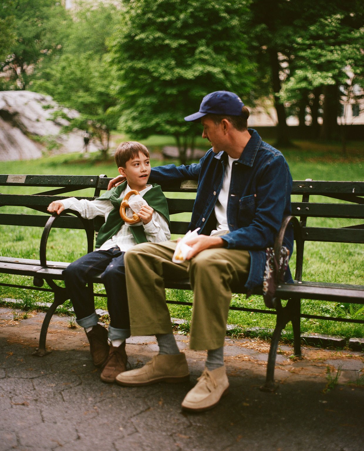 Tom Bannister and his son share pretzels on a park bench.