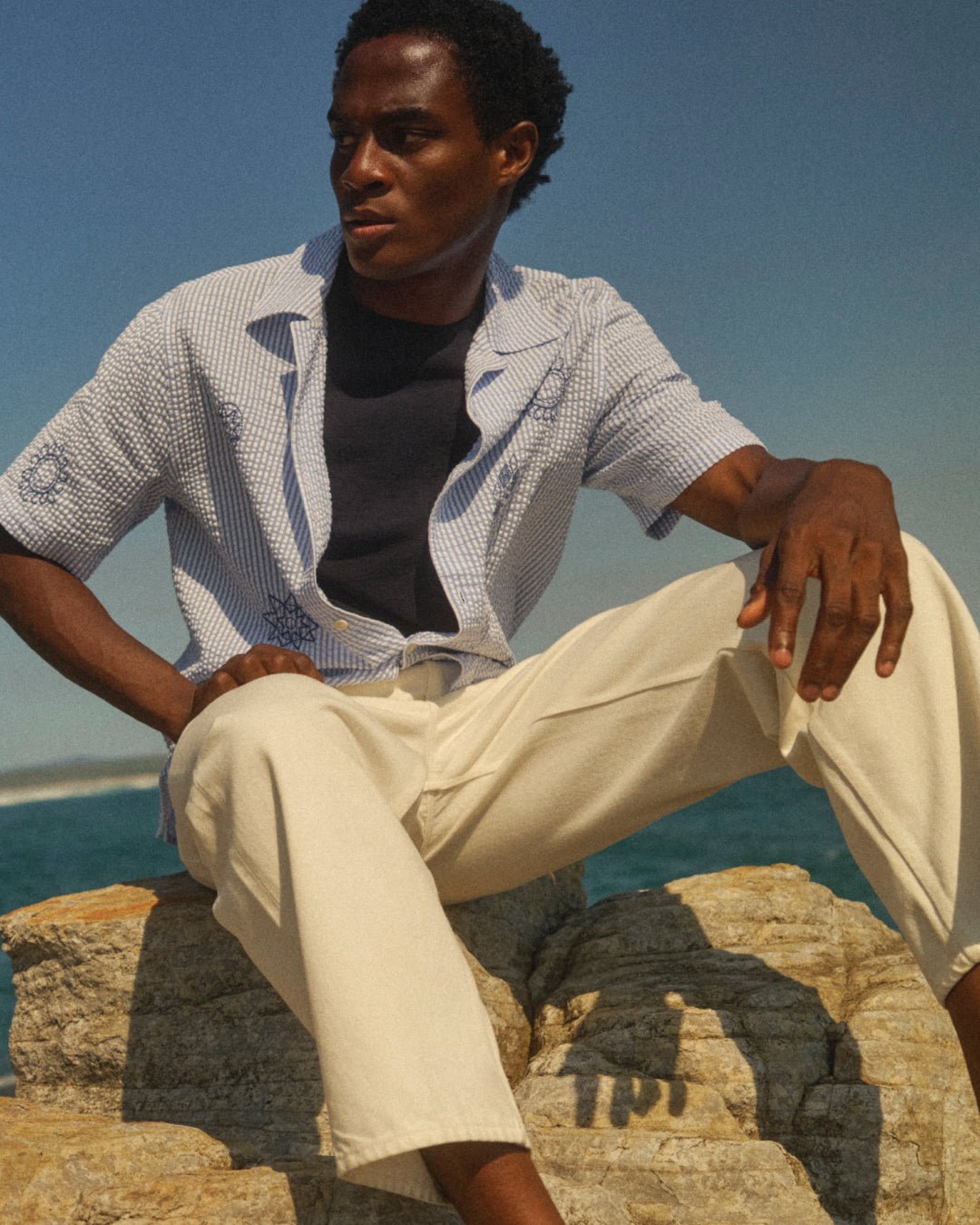 A blue patterned shirt layers over navy jersey and pale jeans.