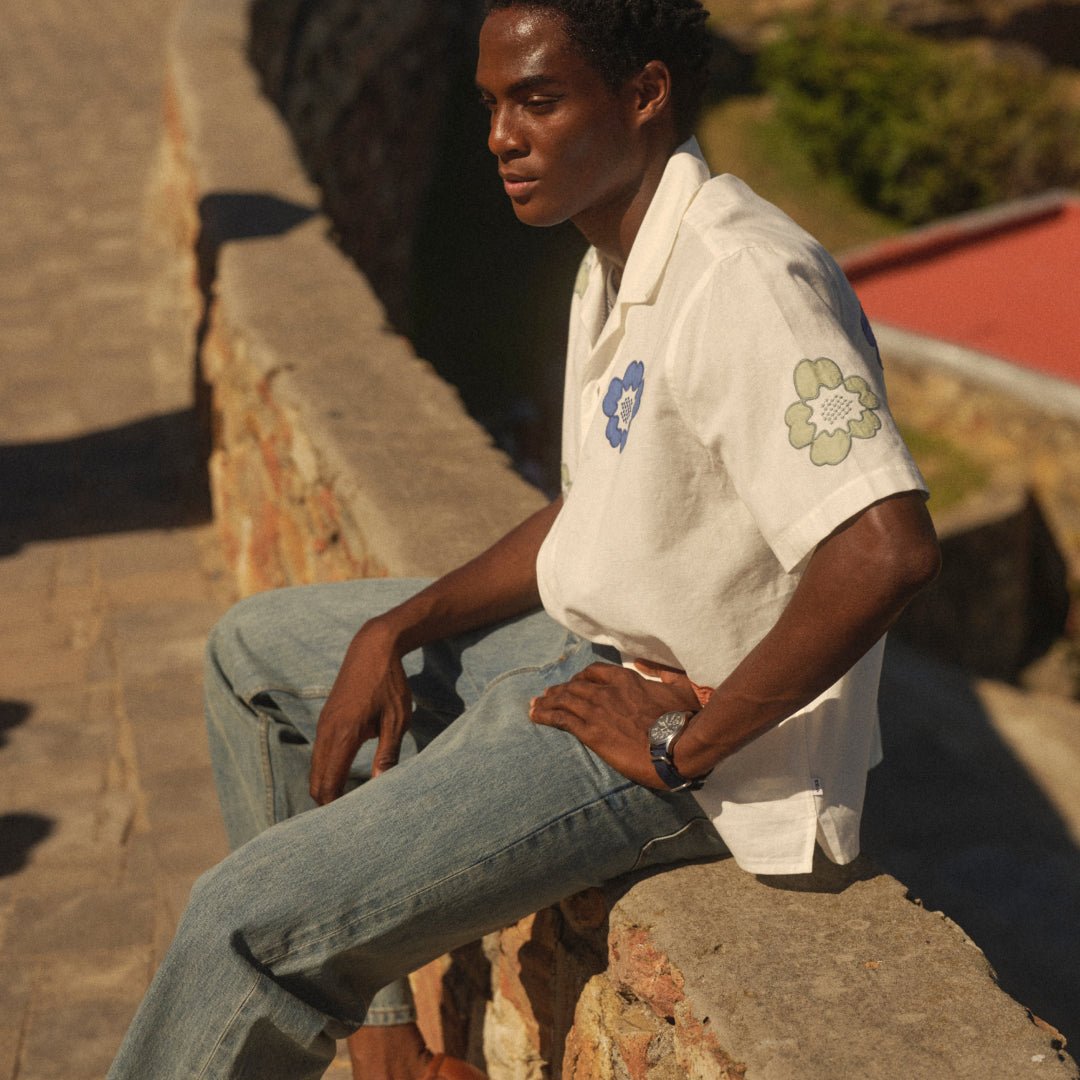 An ecru floral-appliqué shirt pairs with faded blue jeans.