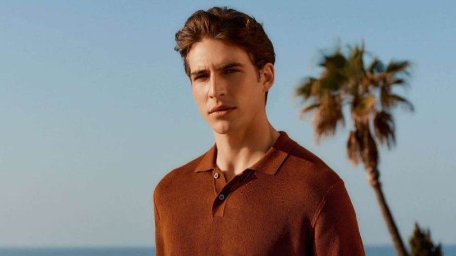 Amerigo Valenti wears a garnet polo with brown trousers beside the coast.