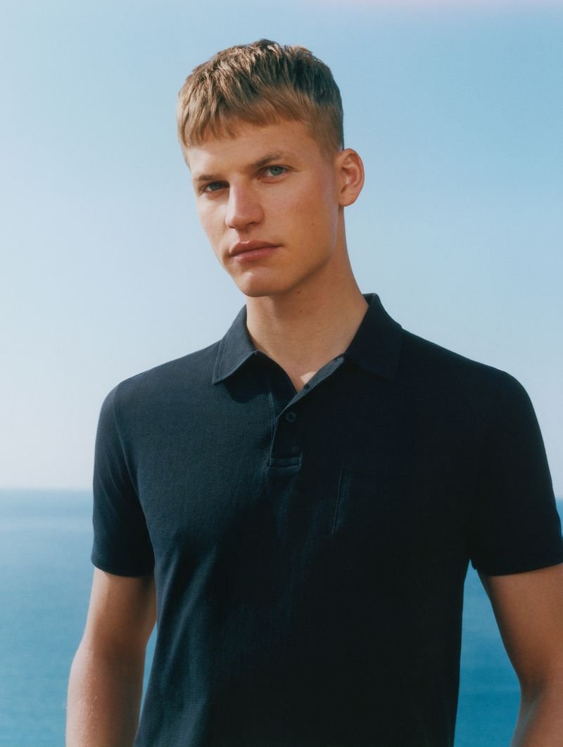 Timo Pan wears a navy Riviera polo against sea and sky.