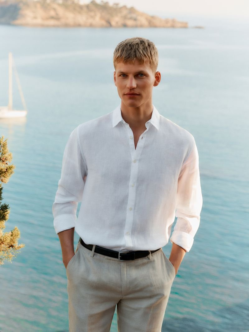 Pan wears a white linen shirt with pale trousers and a dark belt.